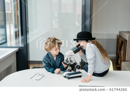 Two clever elementary schoolkids studying chemistry with microscope Two clever elementary schoolkids studying chemistry with microscope 61744260