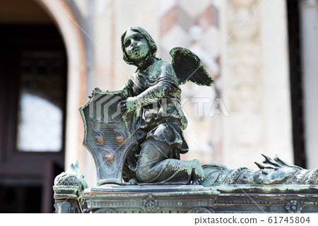 Angel holding a shield with Colleoni Coat of Arms as a decoration of the fence of Bergamo cathedral in Italy Angel holding a shield with Colleoni Coat of Arms as a decoration of the fence of Bergamo cathedral in Italy 61745804