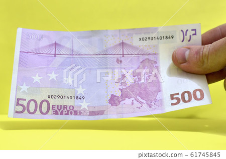 Man's hand holding a big money bill, 500 euros in one hand. 61745845