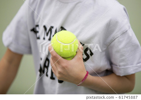 Person holding tennis balls on tennis court 61745887