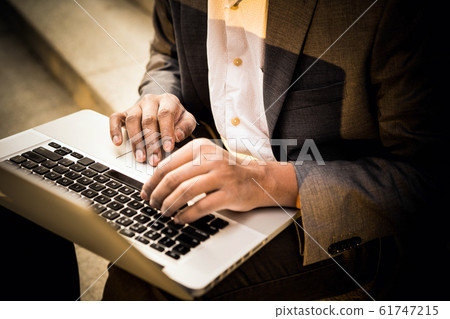 Young mixed race man is sitting with a laptop, and typing Young mixed race man is sitting with a laptop, and typing 61747215