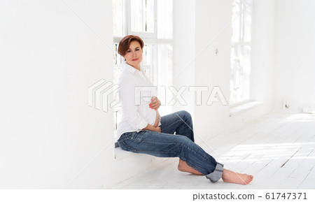 Happy Pregnant Woman Sitting In White Room Happy Pregnant Woman Sitting In White Room 61747371