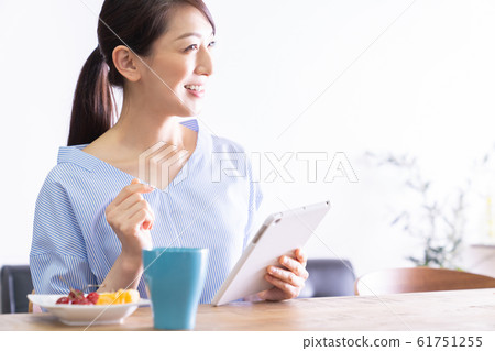 觀看一台片劑計算機的婦女在屋子裡 觀看一台片劑計算機的婦女在屋子裡 61751255