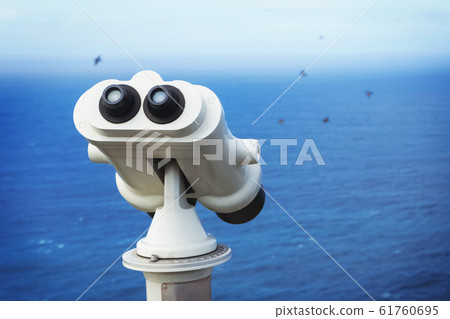 Touristic binocular telescope looking on the blue ocean close-up. 61760695
