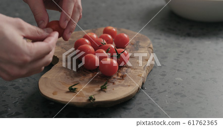man hands remove stems from cherry tomatoes on olive board man hands remove stems from cherry tomatoes on olive board 61762365