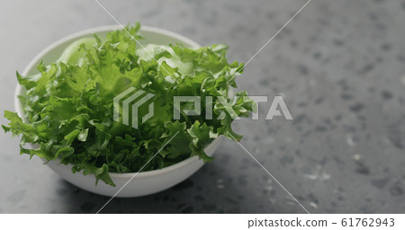 frisee leaves in white bowl on terrazzo surface frisee leaves in white bowl on terrazzo surface 61762943
