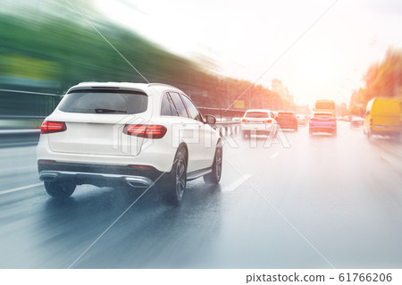 Wet highway after heavy rain with warm sunset evening sun on background. Vehicles riding with high speed by rainy city street road. aquaplaning or hydroplaning effect 61766206