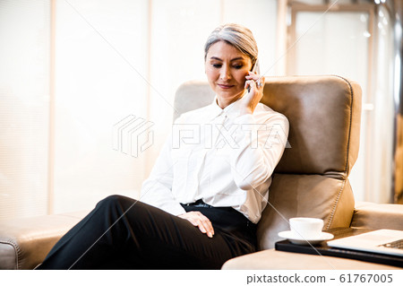 Company boss in the armchair with coffee and phone stock photo 61767005