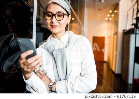 Joyful boss with smartphone in office stock photo 61767119