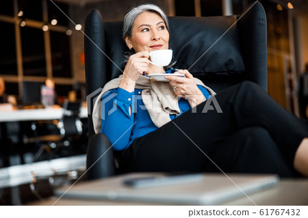 Dreamy woman enjoying coffee and looking away stock photo 61767432