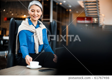 Mirthful lady enjoying tasty coffee at work stock photo 61767498