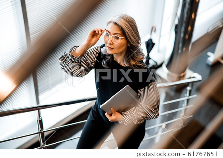 Woman touching the glasses while walking upstairs stock photo 61767651
