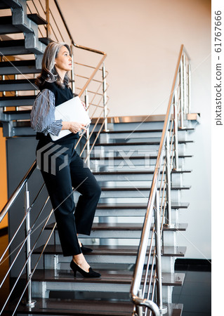 Thoughtful tired woman on the stairs with gadget stock photo 61767666