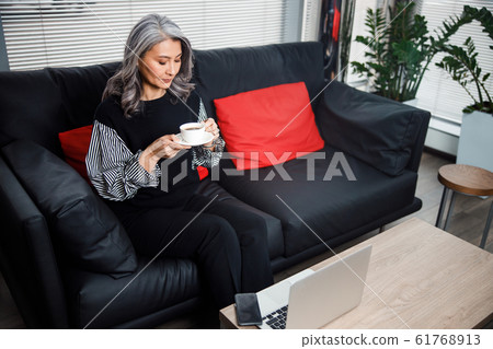 Thoughtful woman looking at her cup stock photo 61768913