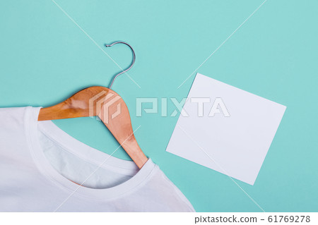 White t-shirt lying on green turquoise background and blank paper card 61769278
