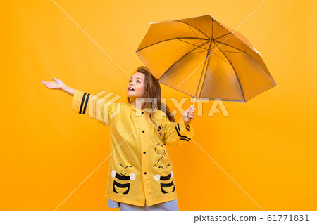 happy joyful girl in a beautiful yellow raincoat in the image of a bee holds a silver umbrella and 61771831