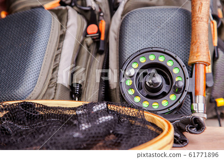 fly fishing rod with a coil and flies lie on old, wooden boards fly fishing rod with a coil and flies lie on old, wooden boards 61771896