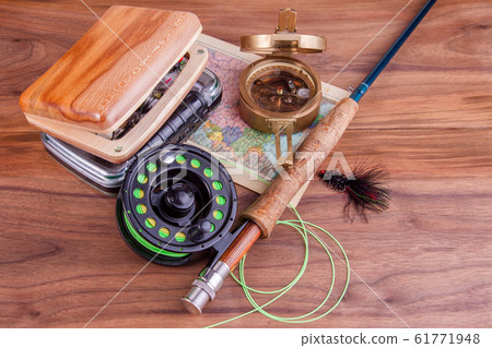 fly fishing rod with a coil and flies lie on old, wooden boards fly fishing rod with a coil and flies lie on old, wooden boards 61771948