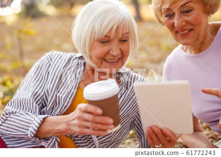 Friends watching videos sitting in the park Friends watching videos sitting in the park 61772243