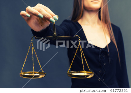 Serious woman holding the justice scale on dark Serious woman holding the justice scale on dark 61772261