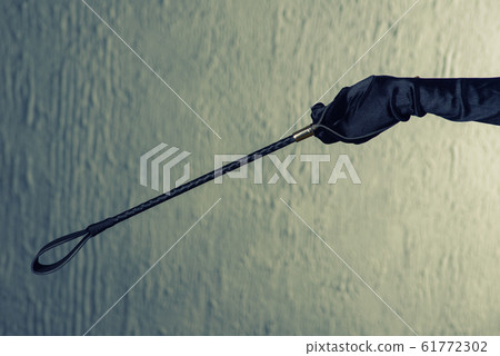 Woman's hand in a satin glove holding a stack. 61772302