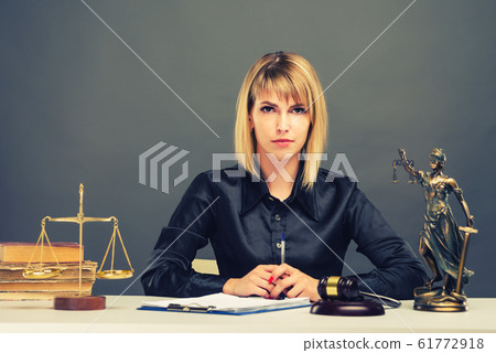 A young fair woman judge works in her office. A young fair woman judge works in her office. 61772918