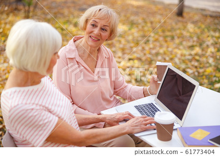 Cheerful aged woman spending morning with her friend Cheerful aged woman spending morning with her friend 61773404