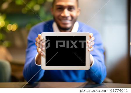 Smiling black man showing blank computer screen Smiling black man showing blank computer screen 61774041