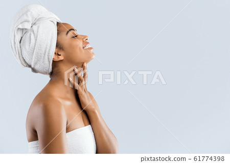 Joyful woman wrapped in towels looking at copy space 61774398