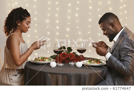 Black couple taking photos of meal in restaurant Black couple taking photos of meal in restaurant 61774647