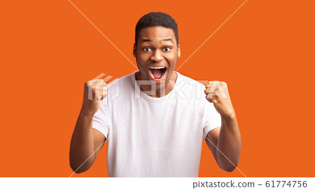 Afro man shouting over orange studio background Afro man shouting over orange studio background 61774756