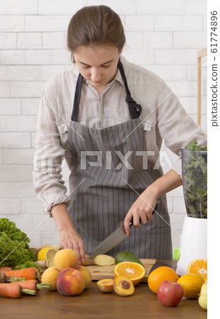 Young woman cutting fruits for making detox smoothie 61774896