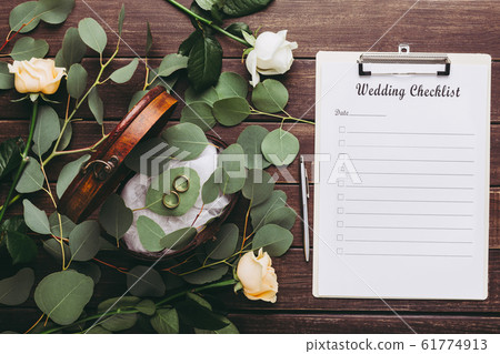Wedding rings and paper planning checklist on wooden table Wedding rings and paper planning checklist on wooden table 61774913