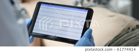 Female doctor hold in hand tablet pc with patient electrocardiogram Female doctor hold in hand tablet pc with patient electrocardiogram 61774914