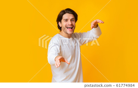 Positive millenial guy dancing and looking at camera, emotionally gesturing Positive millenial guy dancing and looking at camera, emotionally gesturing 61774984