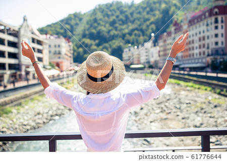 Happy girl at hat on the embankment of a mountain river in a European city. 61776644