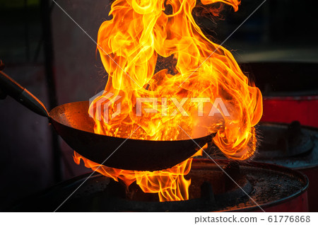 Chef cooking with fire in frying pan 61776868