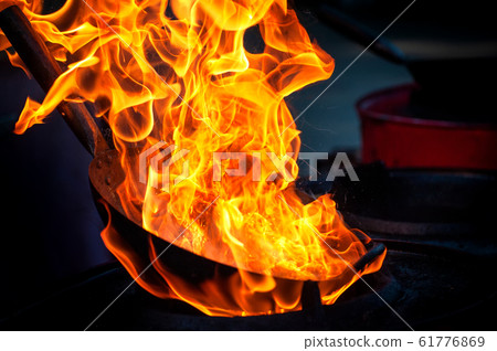 Chef cooking with fire in frying pan 61776869