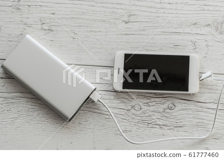 White smart phone charging from silver power bank 61777460