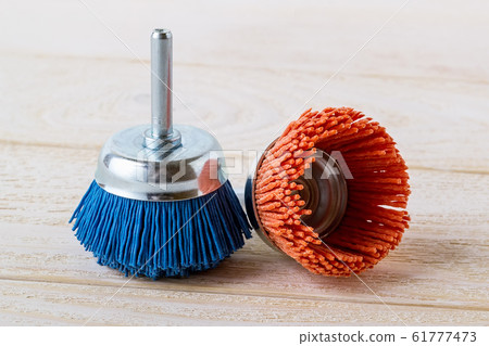 Blue and red nylon abrasive brushes for drill on a white wooden surface. Blue and red nylon abrasive brushes for drill on a white wooden surface. 61777473