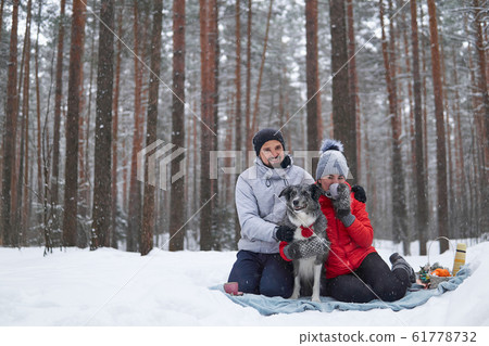 young couple with dog have picnic in snowy forest young couple with dog have picnic in snowy forest 61778732