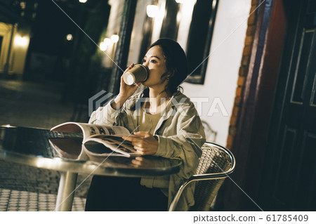 A woman relaxing at a cafe in the evening A woman relaxing at a cafe in the evening 61785409