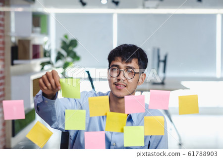 asian businessman looking and writing on sticky asian businessman looking and writing on sticky 61788903