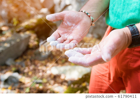 Close-up of a climber's hand in magnesia before an outdoor climbing exercise in the forest. The concept of mountaineering and active sports Close-up of a climber's hand in magnesia before an outdoor climbing exercise in the forest. The concept of mountaineering and active sports 61790411