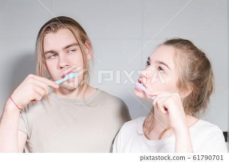 Young couple in bath brush teeth together, looking in mirror. Close-up Young couple in bath brush teeth together, looking in mirror. Close-up 61790701