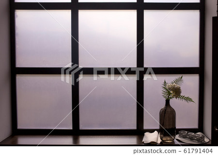 Bottle with a sprig on the windowsill with white frosted glass. 61791404