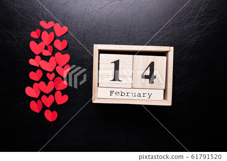 Wooden calendar with the inscription February 14 and with small hearts on a black isolated background. Wooden calendar with the inscription February 14 and with small hearts on a black isolated background. 61791520