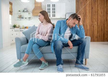 Sad father and daughter sitting on the couch. Sad father and daughter sitting on the couch. 61791855