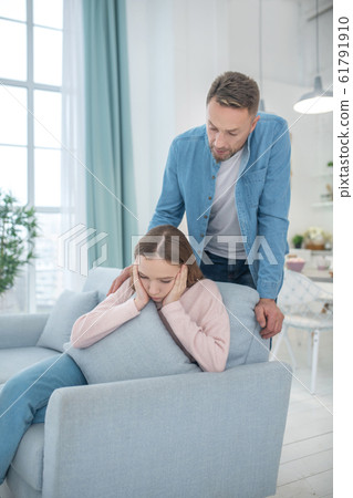 Father is standing behind the back of seated daughter. 61791910