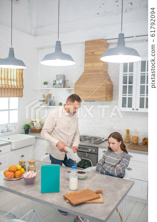 Father preparing healthy breakfast for himself and daughter. Father preparing healthy breakfast for himself and daughter. 61792094